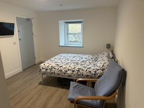a small bedroom with a bed and a chair at Tanerdy - Self Contained Apartment in Carmarthen