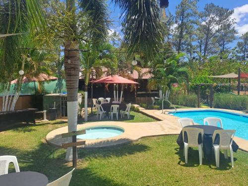 a pool with tables and chairs in a yard at Sunset House Hostel in Liberia