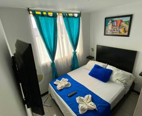 a bedroom with a bed with blue and white pillows at Espectacular Apartahotel full equipado 5min del Parque del Café in Montenegro