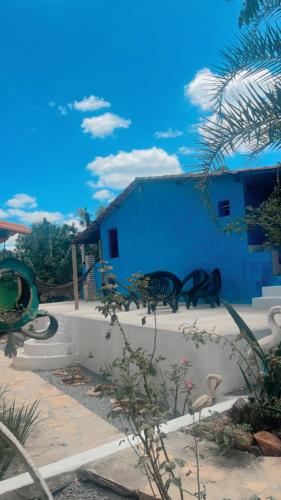 a group of benches sitting next to a blue building at Pousada Ponte da Celoura in Palmeiras