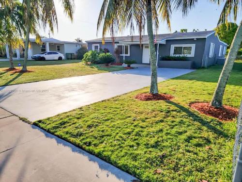 a house with palm trees in front of a driveway at Centrally located Family-business Home in Homestead