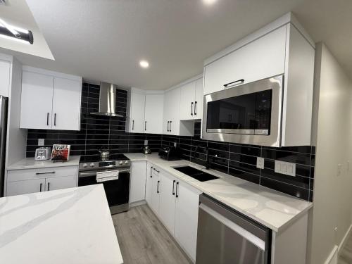 a kitchen with white cabinets and a microwave at Maxti Guest Suite, Northwest Calgary in YYC