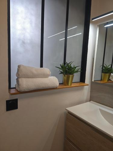 La salle de bains est pourvue d'une fenêtre, de serviettes et d'un lavabo. dans l'établissement lartdeschoix, à Labégude