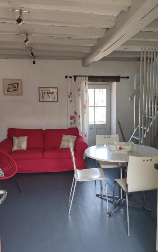 un salon avec un canapé rouge et une table dans l'établissement La maisonette du bateau lavoir, à Semur-en-Auxois