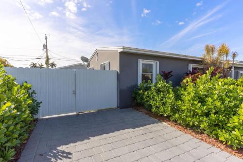 a house with a white fence and bushes at Charming 1 Bedroom Apartment in Homestead