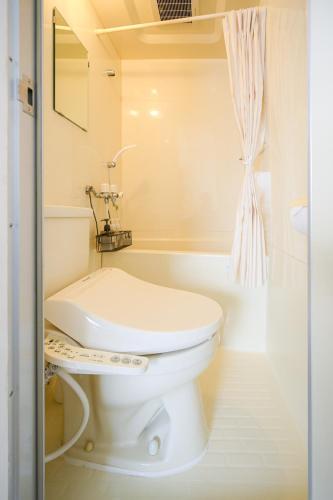 a white bathroom with a toilet and a bath tub at バンビハイツ長嶋304 in Aomori