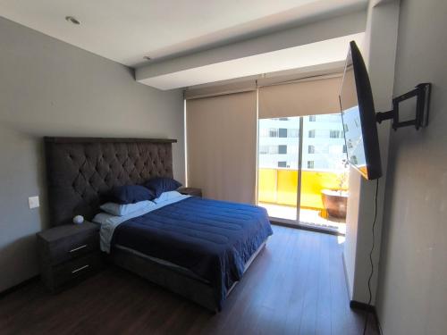 a bedroom with a blue bed and a large window at Cómoda habitación en Santa fe in Mexico City