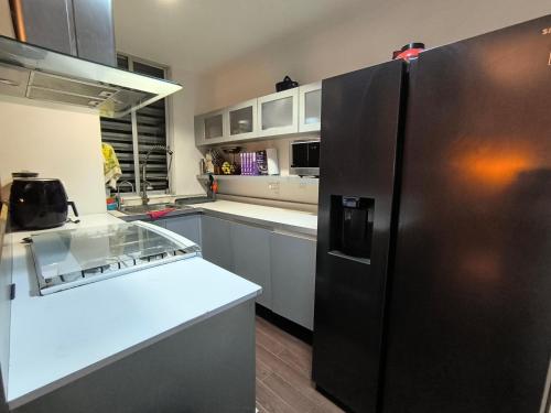a kitchen with a black refrigerator and white cabinets at Cómoda habitación en Santa fe in Mexico City