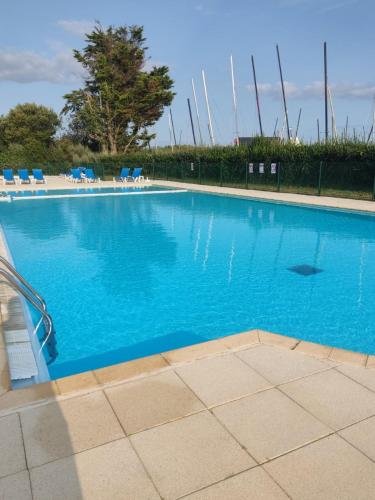 une grande piscine bleue avec des chaises bleues dans l'établissement Résidence Bretagne Douce excellent emplacement 300m de la mer, à Arzon