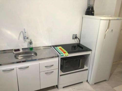 a kitchen with a sink and a microwave and a refrigerator at Pousada Caravela in Penha