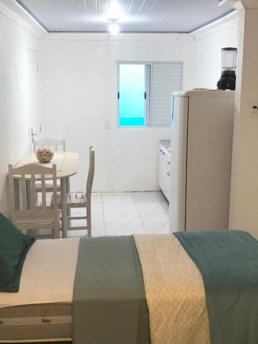 a bedroom with a bed and a table and a refrigerator at Pousada Caravela in Penha