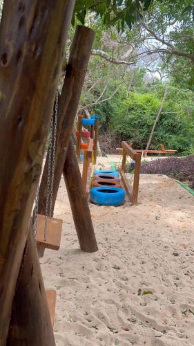 a playground with several wooden swings in the sand at Bruma Homes in Ponta do Ouro