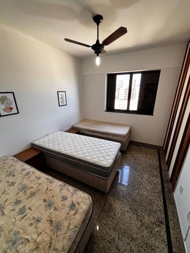 a bedroom with two beds and a ceiling fan at Apartamento Espaçoso com Vista Fabulosa para o Mar in Guarapari