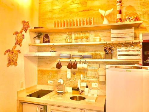 a kitchen with a counter with a sink and a refrigerator at Casa d'Aroeira Residencial Boutique - Centro de Juqueí - 2 quadras do mar - Serviço de Praia - Roupa de Cama 600 fios algodão Egípcio - Toalhas Banho e Praia - Tudo Novo - Estacionamento Interno - Cozinha - Consulte unidades com Ofurô Hidro e Cromoterapia in Juquei