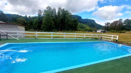 a large blue swimming pool with a white fence at Cabaña viejo Roble in Trape
