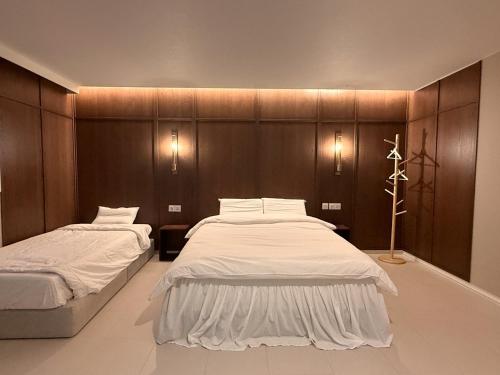 a bedroom with two beds and a wooden wall at Roots House in Busan