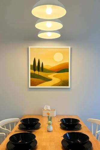 a dining room table with black plates and a painting at Iconic Regency Service Residences - Xin's Home in Bayan Lepas