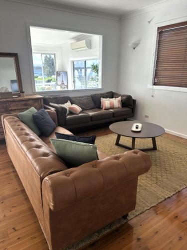 a living room with a brown couch and a table at Sea Breeze Escape - Pet-Friendly Escape - Book 3, Pay for 2! in Greenwell Point