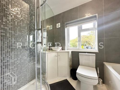 a bathroom with a toilet and a sink and a window at Premium 3BR House, French Doors and Private Garden in Borehamwood