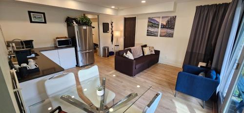 a living room with a glass table and blue chairs at Casa del Rio - Peaceful River Guest Suite -Forests -Mountains -Hiking in Chilliwack
