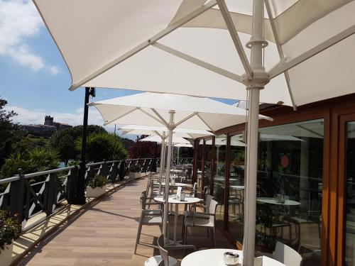 a row of tables with white umbrellas on a balcony at Hotel Faro de San Vicente in San Vicente de la Barquera