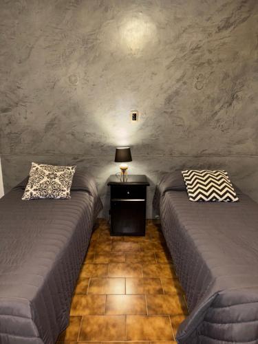 a room with two beds and a table with a lamp at Ganesha in Villa Carlos Paz