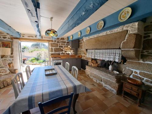 une salle à manger avec une table et une cheminée en pierre dans l'établissement Stone House by Beach in Pont-Aven, à Trégunc