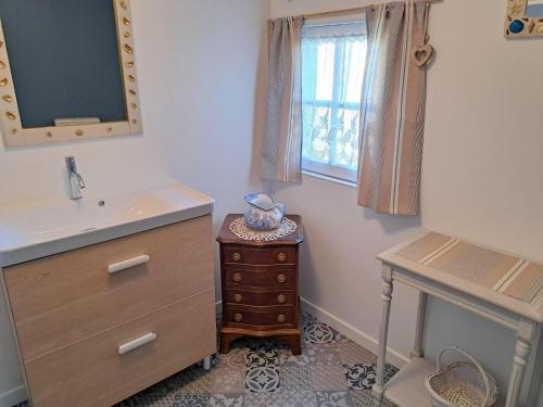 La salle de bains est pourvue d'un lavabo, d'une commode et d'une fenêtre. dans l'établissement Stone House by Beach in Pont-Aven, à Trégunc