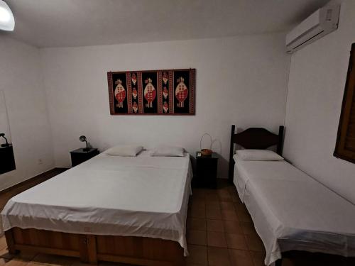 two beds in a room with a picture on the wall at Pousada Pouso do Frade in Pirenópolis