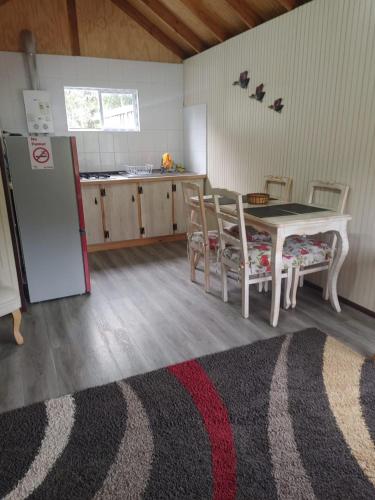 a kitchen with a table and chairs and a refrigerator at Cabañas Costabudy in La Ensenada