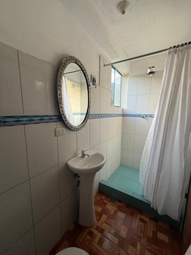 a bathroom with a sink and a mirror and a shower at Vertigo Climbing Hostel in Urubamba