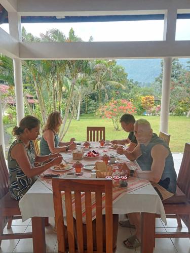 a group of people sitting at a table eating food at Guesthouse Rumah Senang in Kalibaru