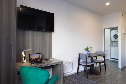 a room with a desk with a laptop and a table with chairs at Quest on Eden Auckland CBD Apartment Hotel in Auckland