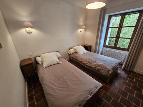 two beds in a small room with a window at Maison ancienne en campagne avec jardin clos - Animaux acceptés - Proche vignobles Chinon - FR-1-381-440 in Parçay-sur-Vienne