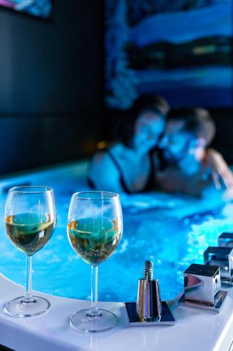 two glasses of wine on a table in a swimming pool at Moments de douceur - Suite Laponie et Suite Tahiti in Boulieu-lès-Annonay
