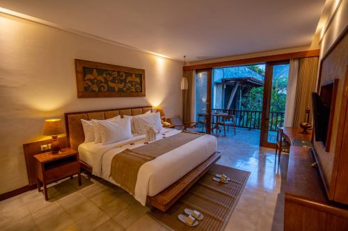 una camera con un grande letto e un balcone di Purana Suite Ubud ad Ubud
