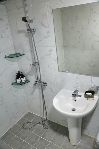 a white bathroom with a sink and a mirror at Gotaya Guesthouse in Andong