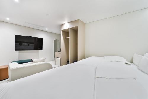 a white bedroom with a large bed and a couch at 호텔그랑파리 in Gwangju