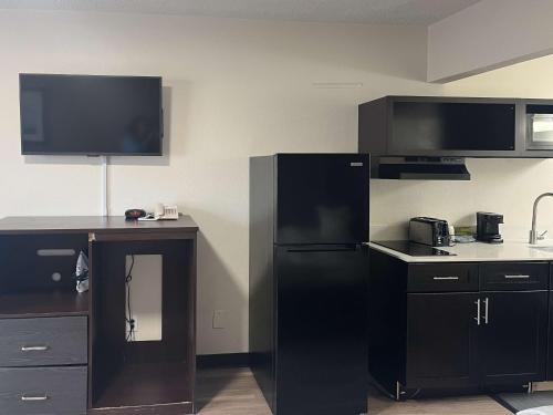 a kitchen with a black refrigerator and a desk at Studio 6 Charlotte, NC – Airport South in Charlotte