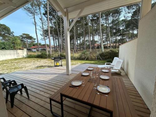une table et des chaises en bois sur une terrasse en bois dans l'établissement Villa lumineuse proche plage pour 8 personnes - FR-1-831-5, à Biscarrosse