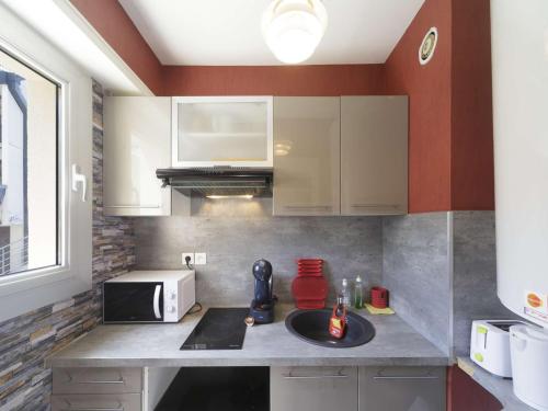 une cuisine avec un évier et un micro-ondes dans l'établissement Appartement 4 pers, 1 chambre, balcon pied de pistes Gourette - FR-1-400-138, à Eaux-Bonnes