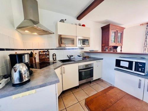 une cuisine avec des armoires blanches et un four à plaques de cuisson dans l'établissement Maison familiale proche plage à Quiberon - FR-1-478-315, à Quiberon