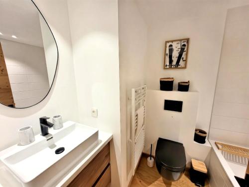 une salle de bain blanche avec un lavabo et un miroir dans l'établissement Confort élé gant avec terrasse, idéal pour famille - FR-1-598-187, aux Gets