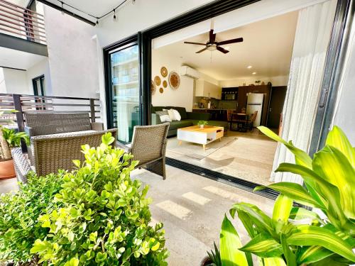 a patio with chairs and a living room at Perfect Condo at Arenis, Oceanview Pool and Gym in Playa del Carmen