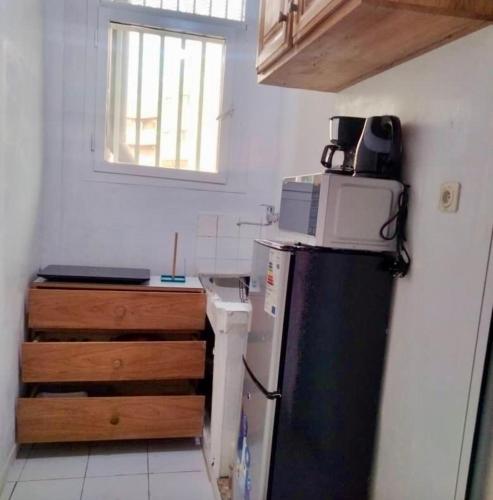 a kitchen with a microwave on top of a refrigerator at Appartement Hypercentre Yaoundé in Yaoundé