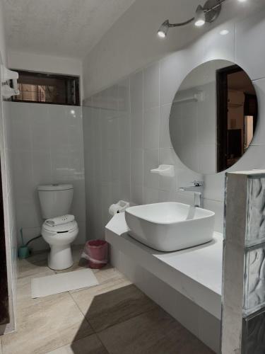 a bathroom with a sink and a toilet and a mirror at Hotel San Juan in Puerto Escondido