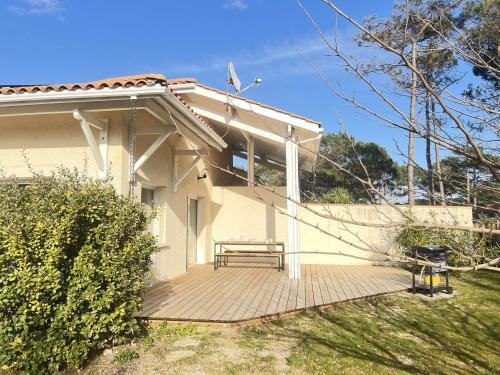 une maison avec un banc sur une terrasse en bois dans l'établissement Villa Spacieuse Proche Plage, 8 Pers. - FR-1-831-3, à Biscarrosse