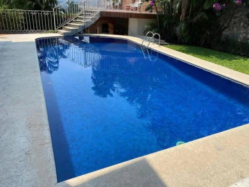 a swimming pool with blue water in a yard at Casa Bugambilia in Temixco