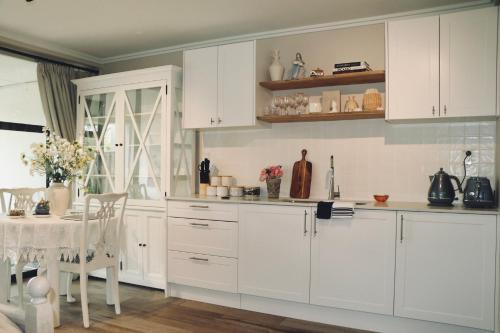 a kitchen with white cabinets and a dining table at Maison de Hobson Luxury guest suite in Auckland