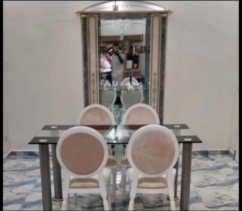 a dining room table with three chairs and a mirror at Appartement Hypercentre Yaoundé in Yaoundé